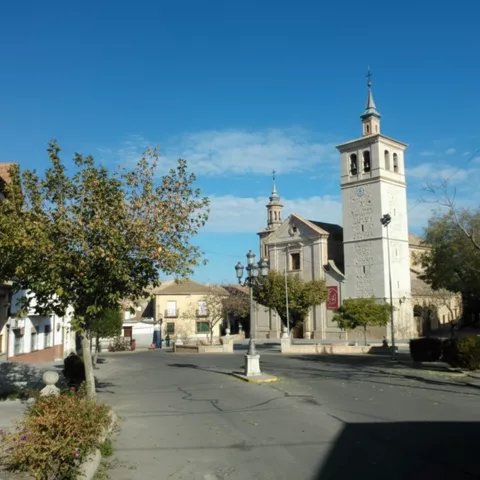 Plaza tranquila con iglesia de torre alta y edificios bajos alrededor