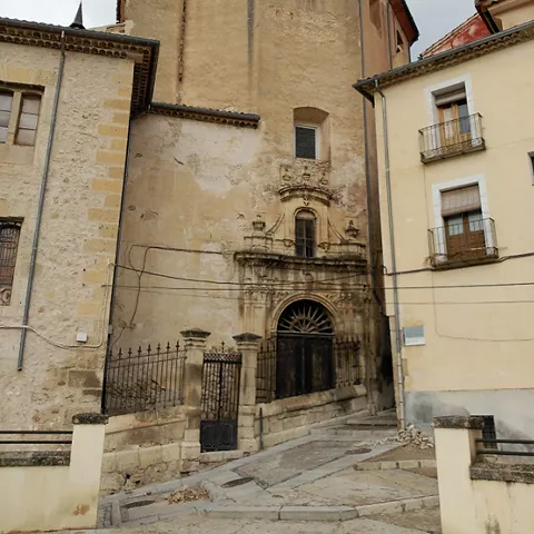 Fachada posterior de edificio antiguo con muros de piedra y pequeñas ventanas.