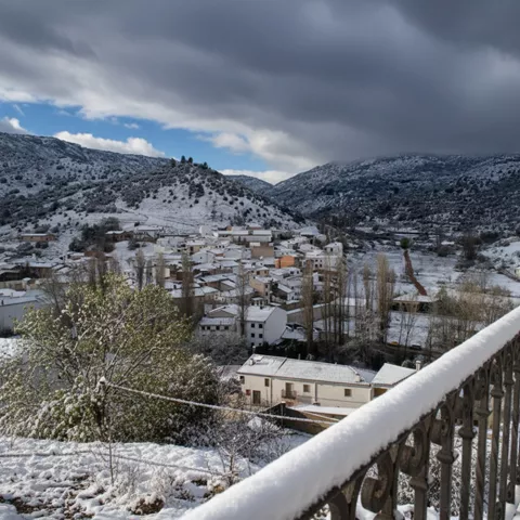 Vista panorámica de un pueblo cubierto de nieve entre montañas.