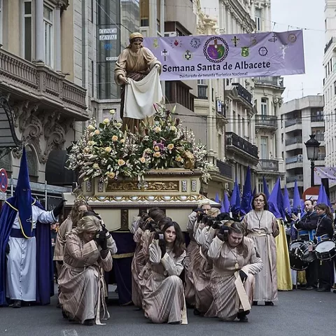 Paso religioso portado por costaleros con banda y público alrededor.