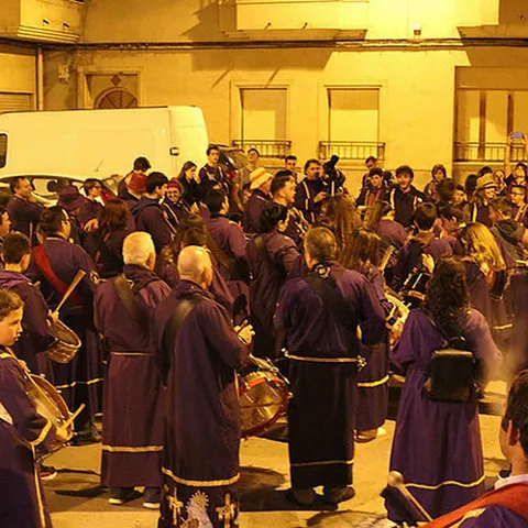 Procesión nocturna con numerosos tamborileros iluminados por farolas.