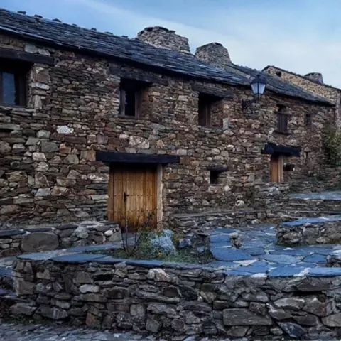 Plaza de piedra rodeada de viviendas tradicionales con pozo central.