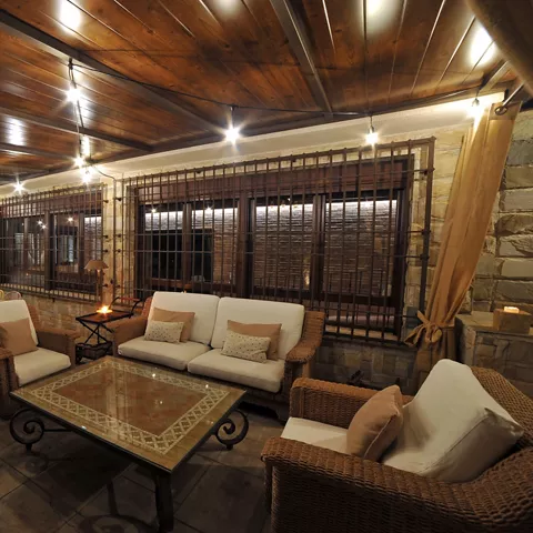 Amplio porche cubierto con cómodos sofás y mobiliario de exterior, ideal para relajarse, conversar y disfrutar del aire libre durante todo el año en Casa Rural Alma del Tajo.
