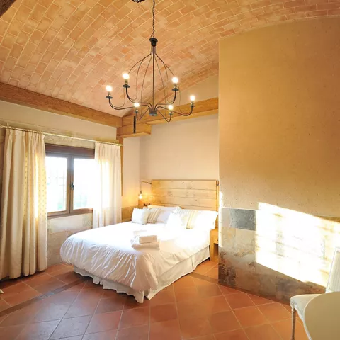 Amplia habitación con cama de matrimonio, abundante luz natural, decoración rústica y un ambiente acogedor para disfrutar de una estancia confortable en Casa Rural Alma del Tajo, Toledo.