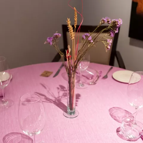 Mesa con mantel rosa y centro floral seco