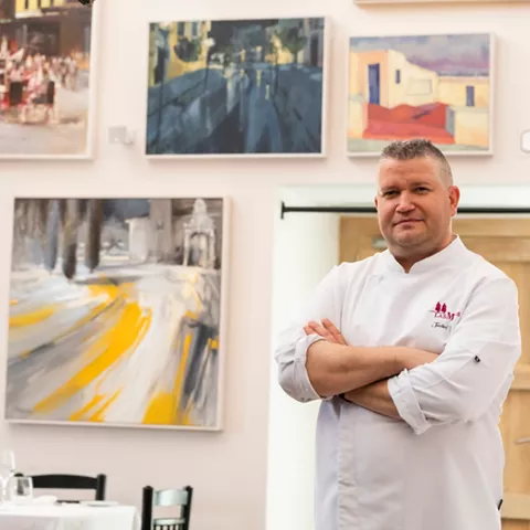 Chef posando en comedor con cuadros