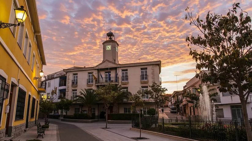 Plaza principal con ayuntamiento y fuente al atardecer