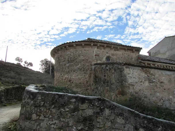 Ábside románico de piedra en entorno rural.