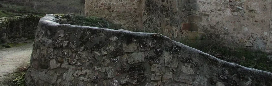 Ábside románico de piedra en entorno rural.