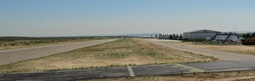 Vista lateral de pista y edificios técnicos en un aeródromo.
