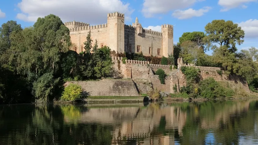 Fortaleza de piedra junto a un río y vegetación frondosa