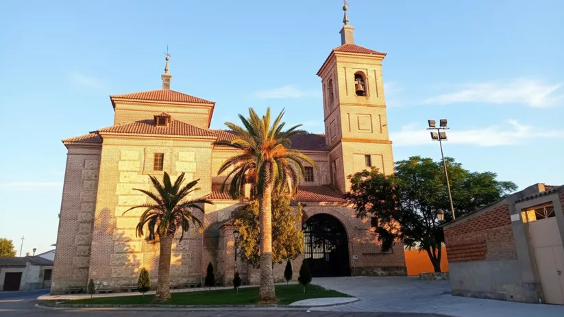 Iglesia de ladrillo con torre campanario y palmeras