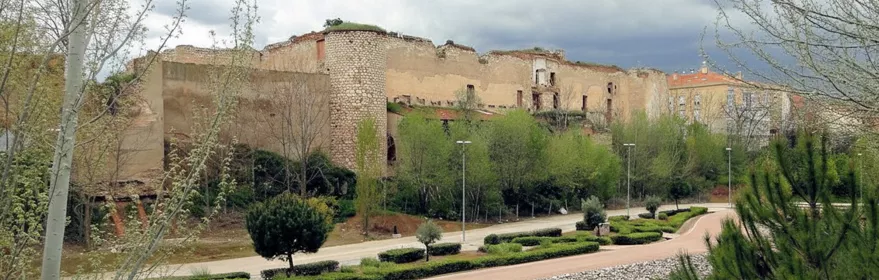 Murallas en ruinas junto a parque y estanque.