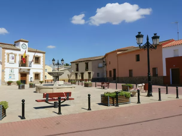 Plaza mayor con edificio municipal, fuente central y bancos