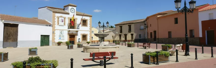 Plaza mayor con edificio municipal, fuente central y bancos