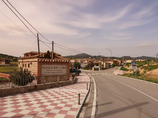 Entrada a la localidad con carretera, acera y viviendas al fondo