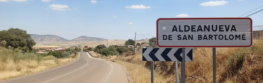 Señal de carretera junto a vía rural con paisaje abierto