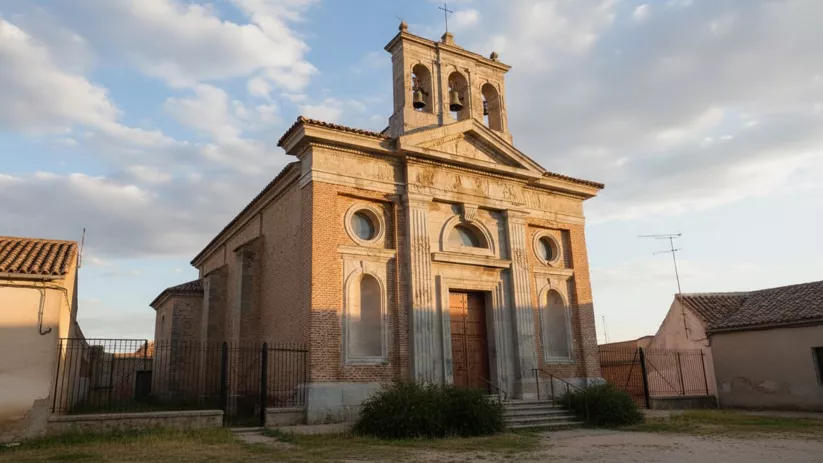 Vista lateral de la iglesia de Almuradiel al atardecer, con fachada de ladrillo y detalles arquitectónicos tradicionales.