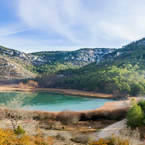 Laguna rodeada de montañas y pinar en paisaje natural