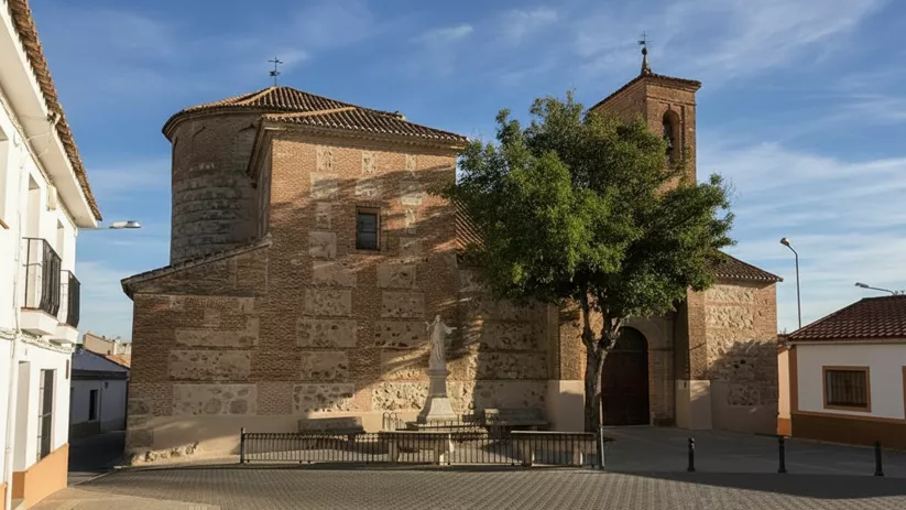 Iglesia de piedra con torre y plaza empedrada