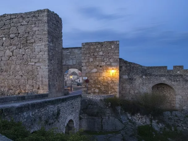 Muralla de piedra al anochecer con arco iluminado