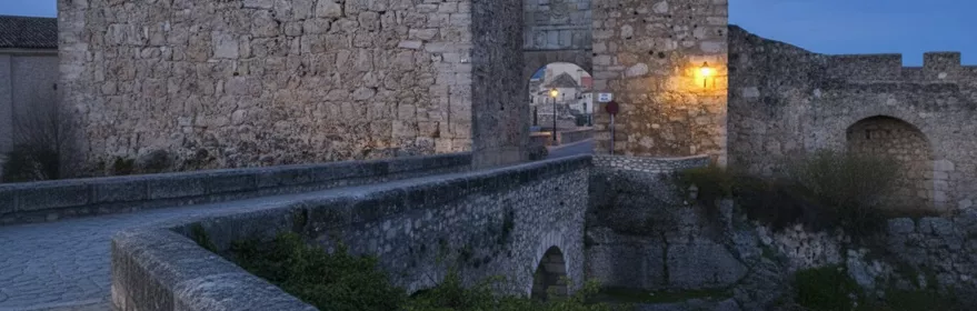 Muralla de piedra al anochecer con arco iluminado