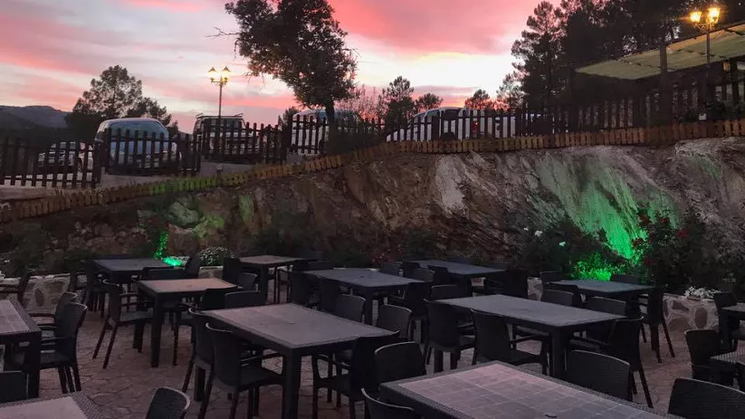 Terraza al atardecer con mesas vacías y cielo rosado