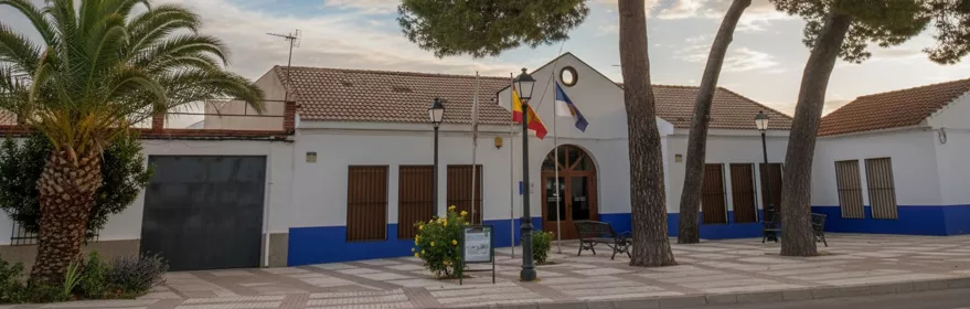 Fachada consistorial con banderas y plaza arbolada