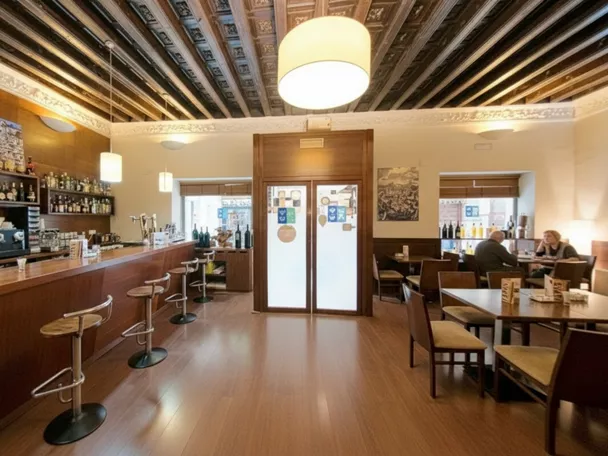 Bar de madera con taburetes y mesas al fondo