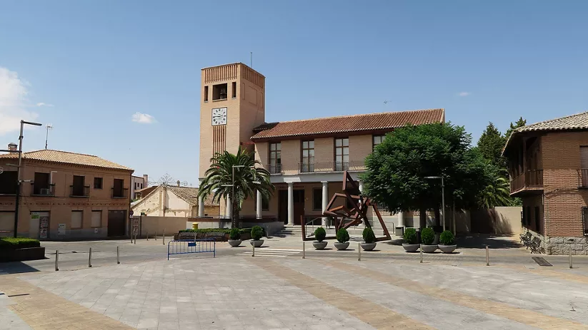 Plaza amplia con edificio institucional y torre con reloj
