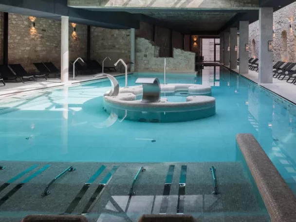 Piscina interior de spa con chorros y tumbonas