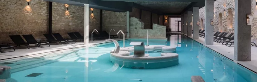 Piscina interior de spa con chorros y tumbonas