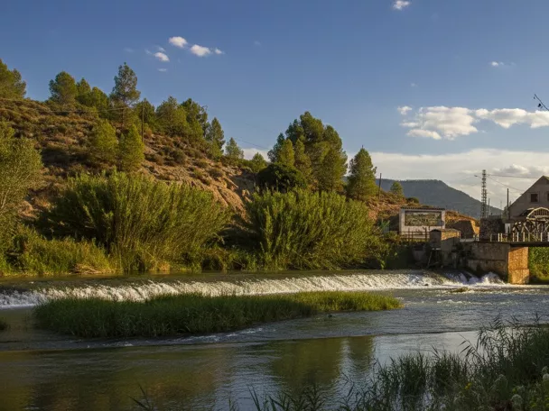Río con pequeño azud y casa junto a la orilla