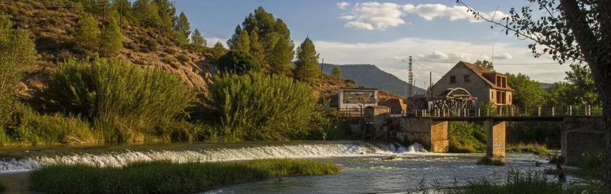 Río con pequeño azud y casa junto a la orilla