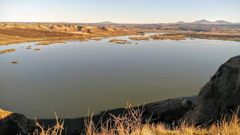 Panorámica de un embalse rodeado de colinas y vegetación seca