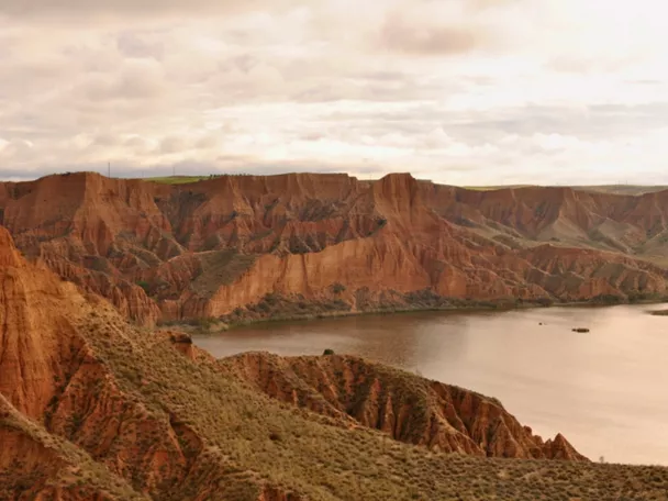 Acantilados de tierra rojiza junto a un embalse