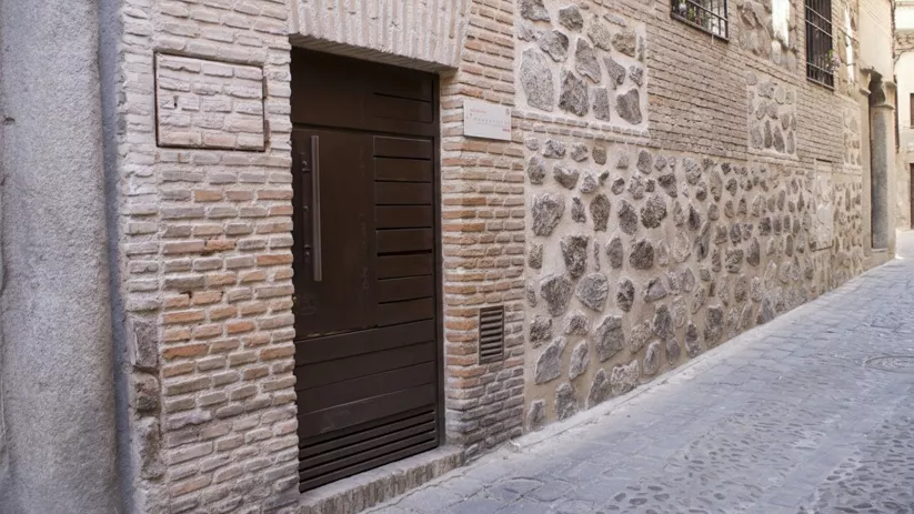 Fachada de ladrillo y piedra en calle estrecha con puerta moderna.