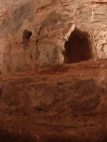 Estructura excavada en roca con iluminación cálida y pasarela.