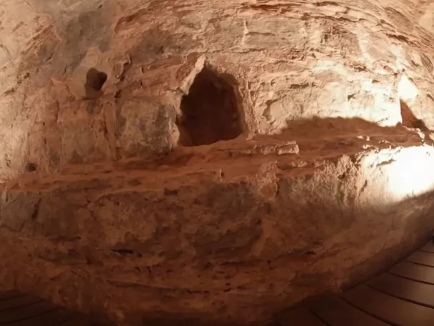 Estructura excavada en roca con iluminación cálida y pasarela.