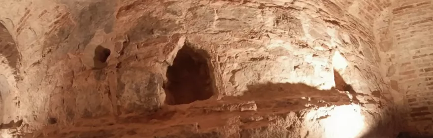 Estructura excavada en roca con iluminación cálida y pasarela.