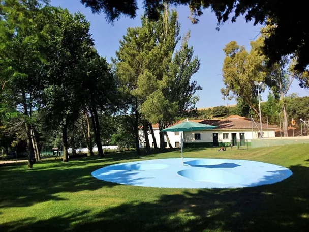 Zona de juegos de agua sobre césped con sombrilla central