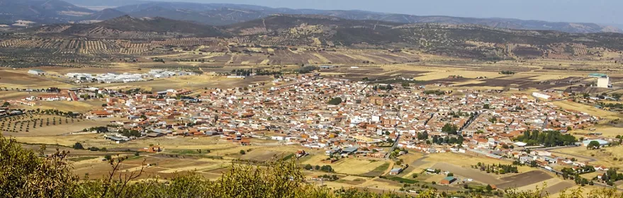 Vista panorámica de un núcleo urbano rodeado de campos y sierras
