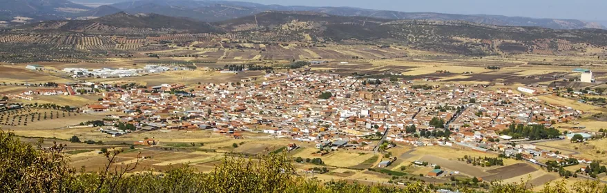 Vista panorámica de un núcleo urbano rodeado de campos y sierras