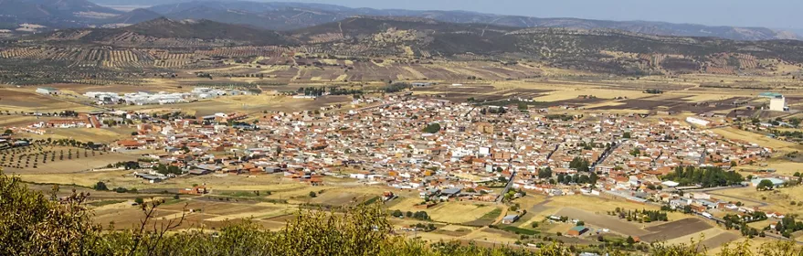 Vista panorámica de un núcleo urbano rodeado de campos y sierras