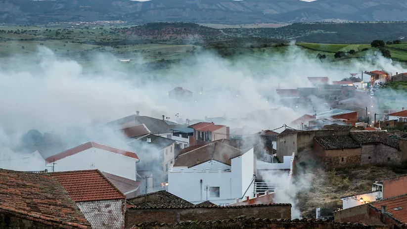 Niebla cubriendo las casas al amanecer con el paisaje rural al fondo