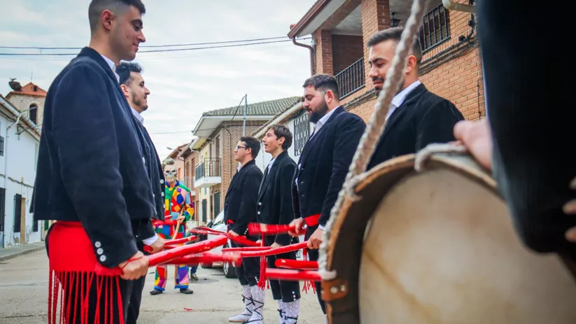 Grupo de hombres tocando palos junto a un tambor.