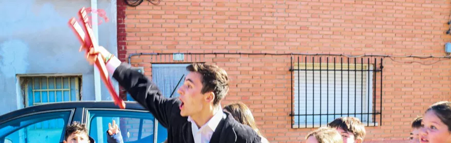 Jóvenes con trajes tradicionales y palos rojos en la calle.