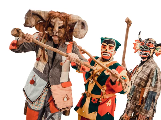 Personas con máscaras y trajes coloridos sosteniendo palos.