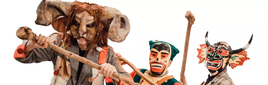 Personas con máscaras y trajes coloridos sosteniendo palos.