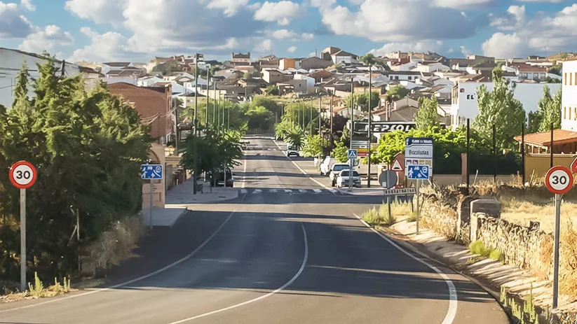 Carretera de entrada con señalización y viviendas
